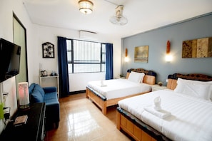 Habitación de hotel con dos camas, televisión, escritorio y ventana con cortinas.