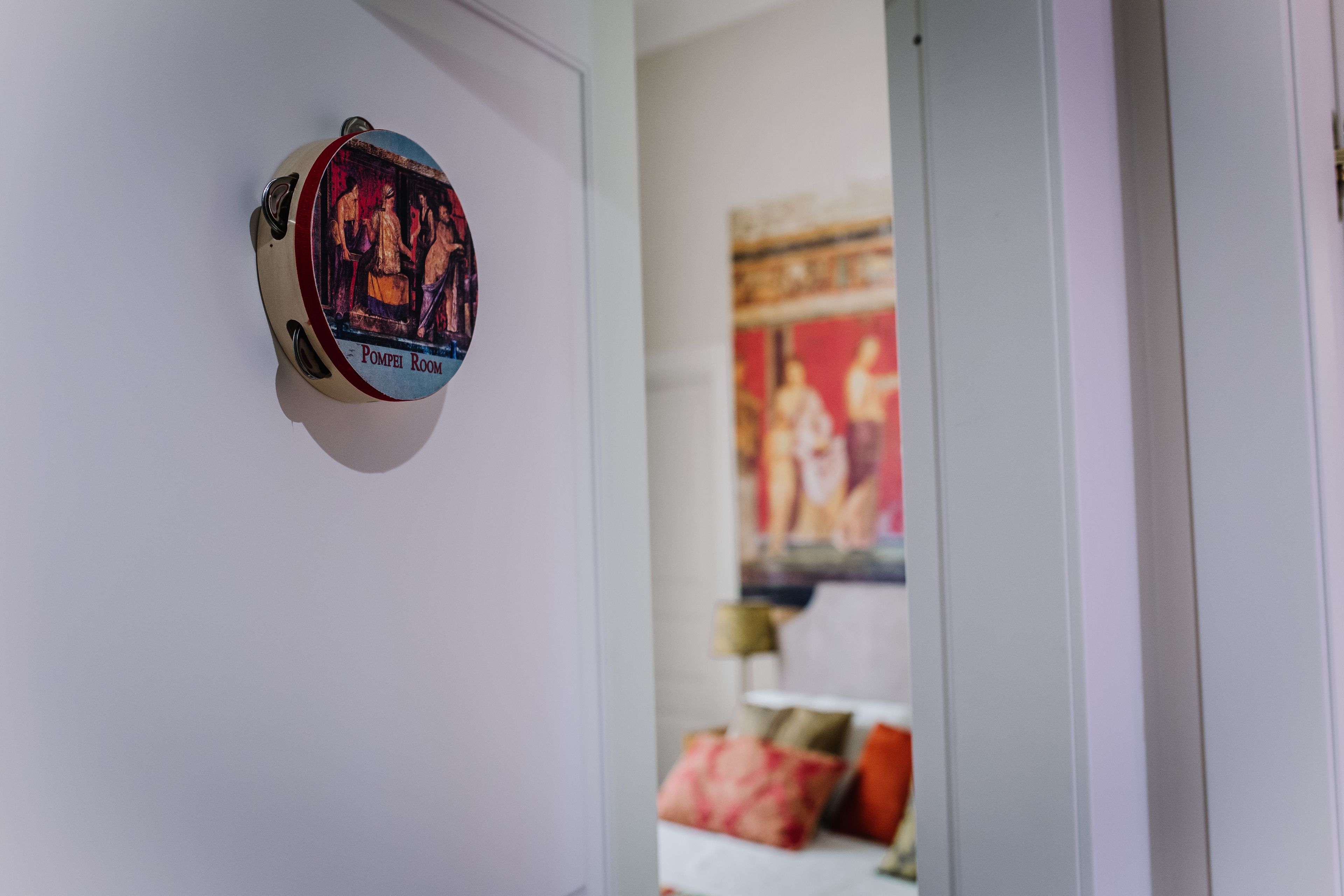 A door with a circular artwork labeled "Pompei Room" and a painting in the background.