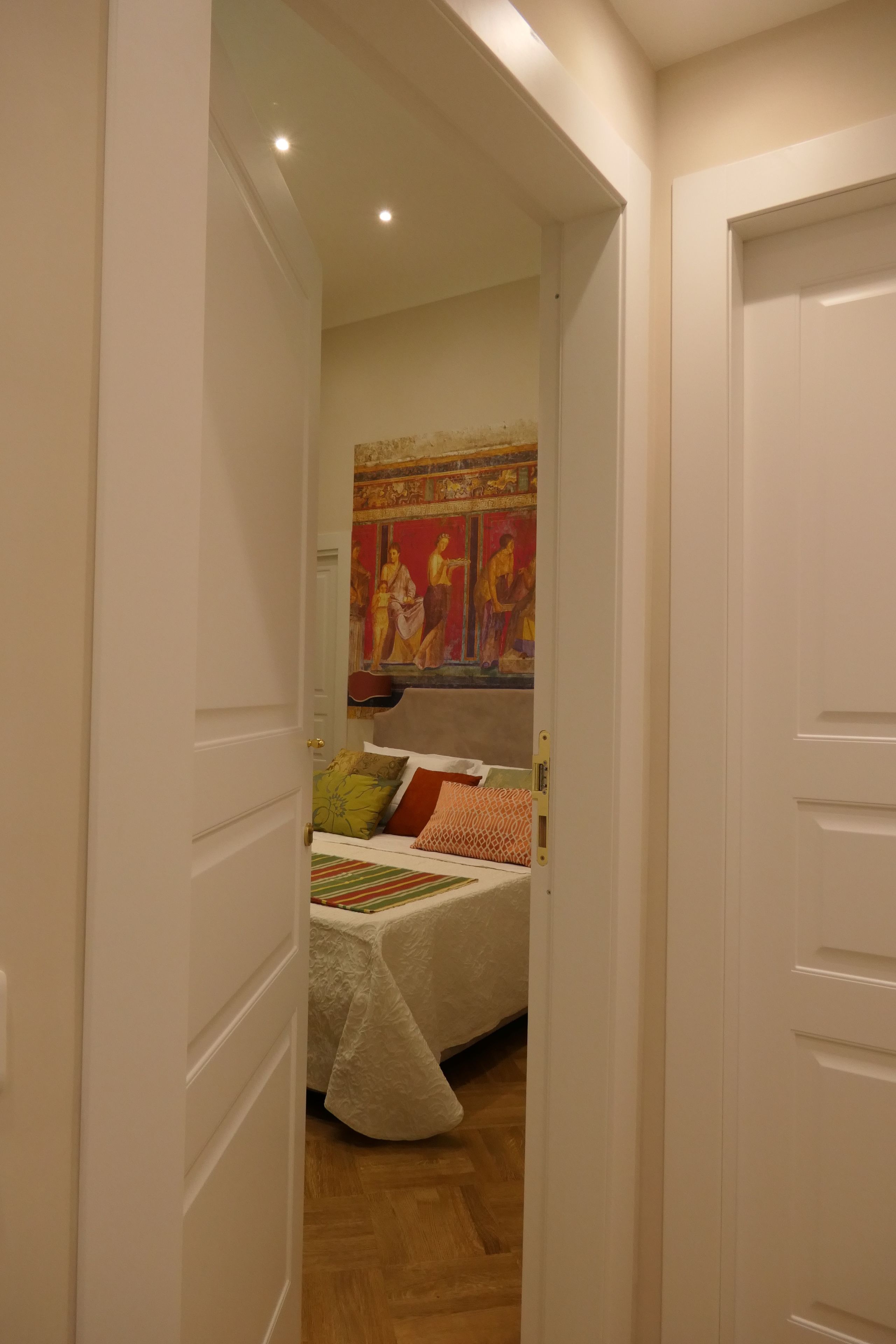 A bedroom with a bed, pillows, and a painting on the wall.