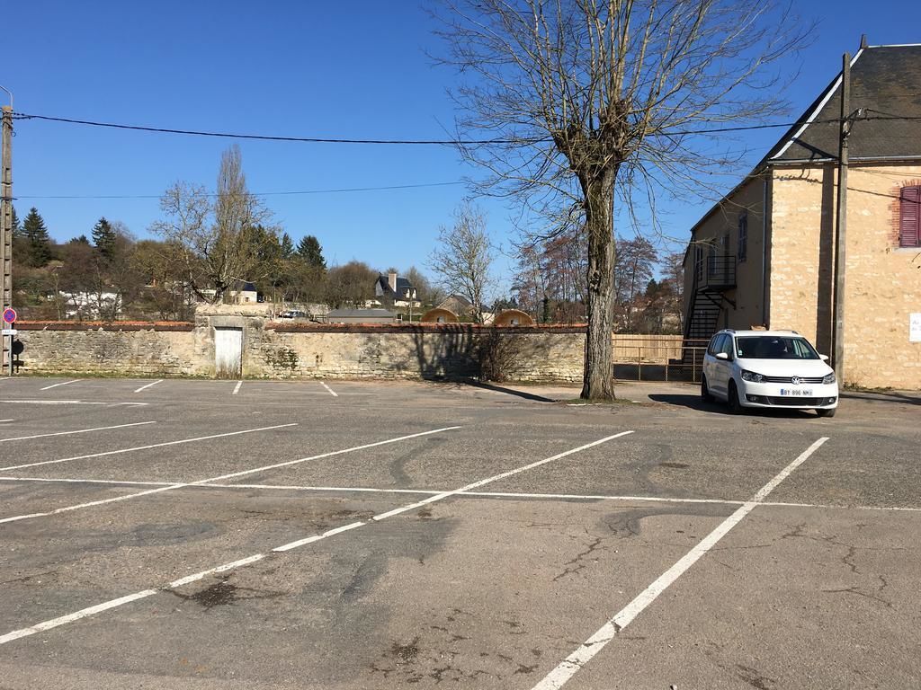 A parking lot with a white car parked near a building with a brick facade.
