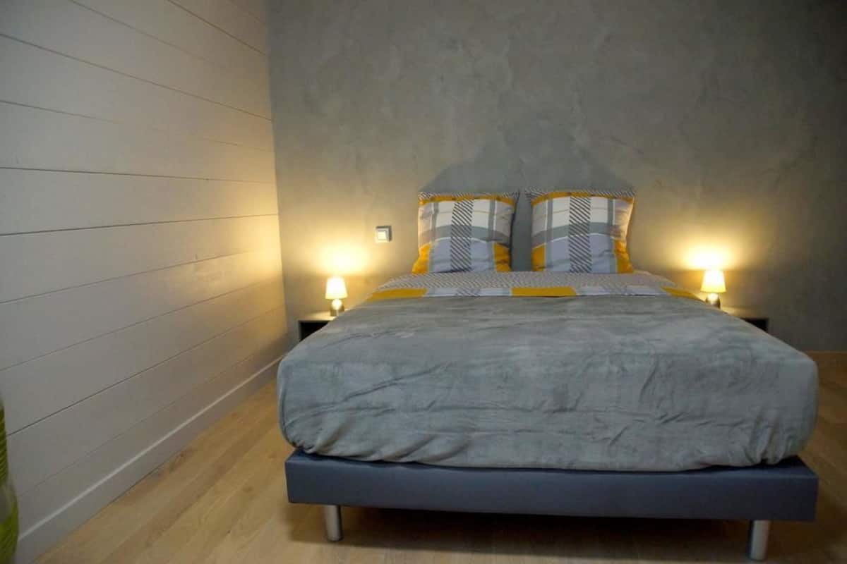 A bedroom with a bed, two bedside tables, and two wall-mounted lamps.
