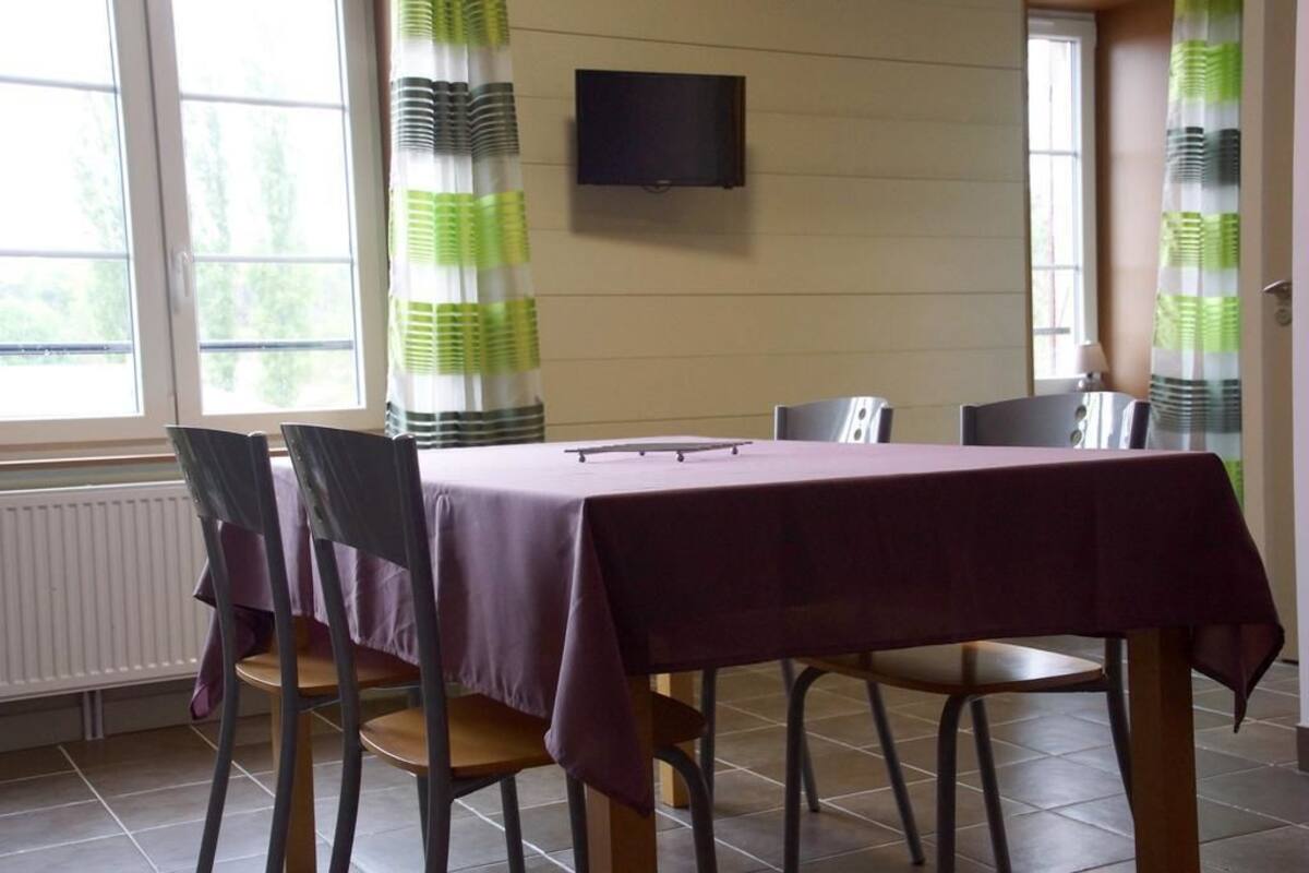 A dining area with a table covered by a purple tablecloth, surrounded by four chairs.