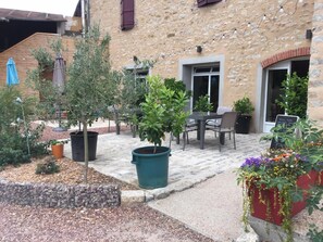 A courtyard with potted plants, a table, and chairs, surrounded by stone walls and a building with a rustic appearance. - Au Foudre du Bazois (Chatillon en Bazois)