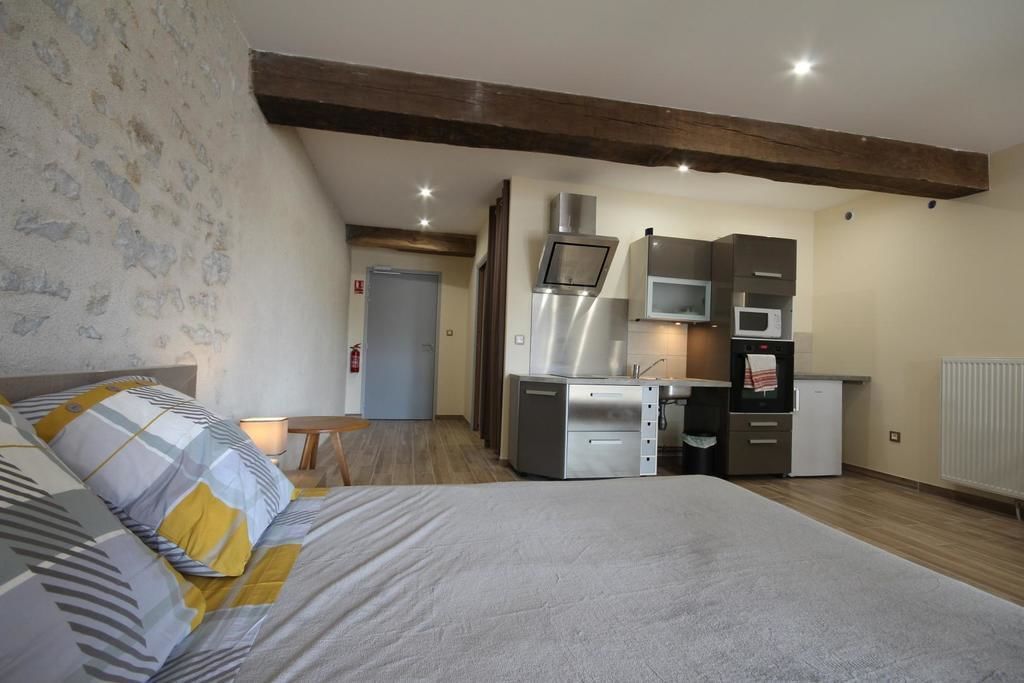 Una habitación compacta con cama, kitchenette y una puerta que da a otra estancia.