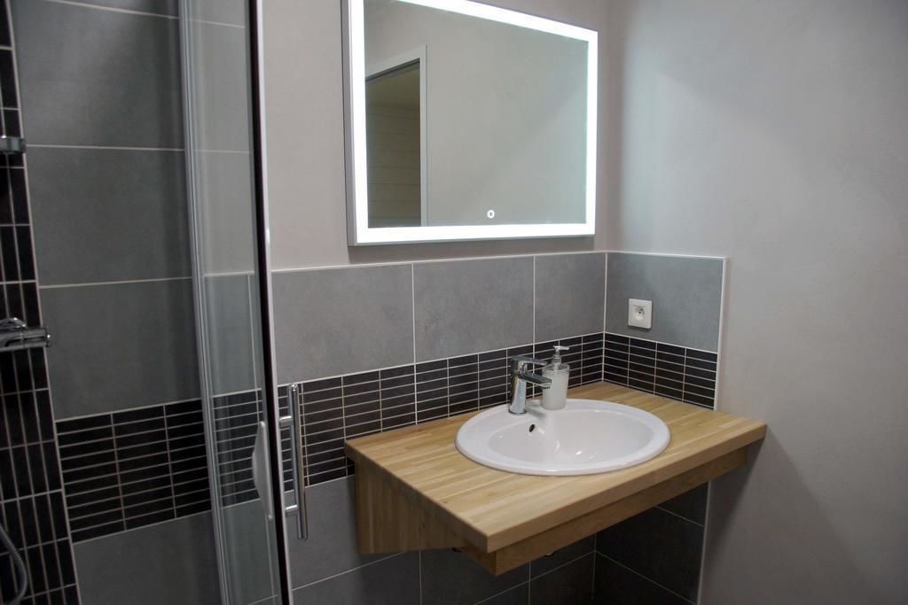 A bathroom with a wooden vanity, a white sink, and a mirror above it.