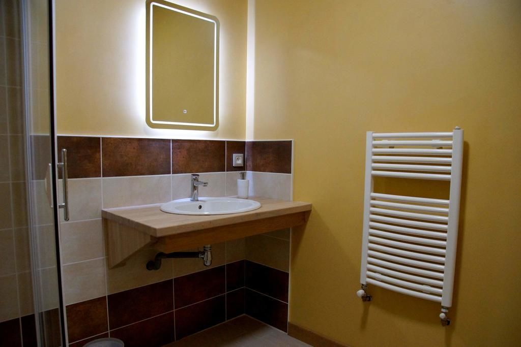 Un baño con lavamanos, espejo, toallero y paredes de azulejos.