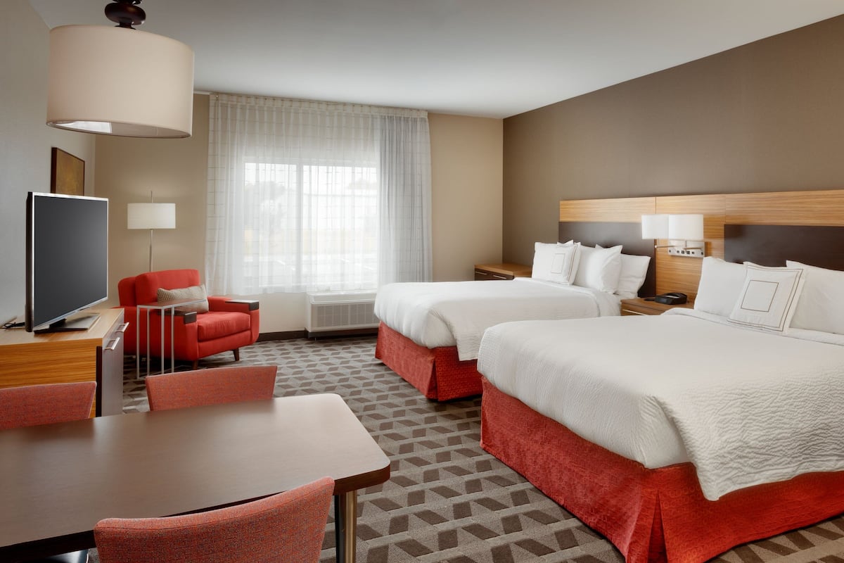 Une chambre d’hôtel avec deux lits, une télévision, un bureau et une chaise.