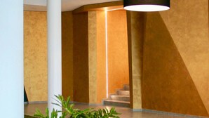 Un interior moderno con una escalera, una columna e iluminación colgante.