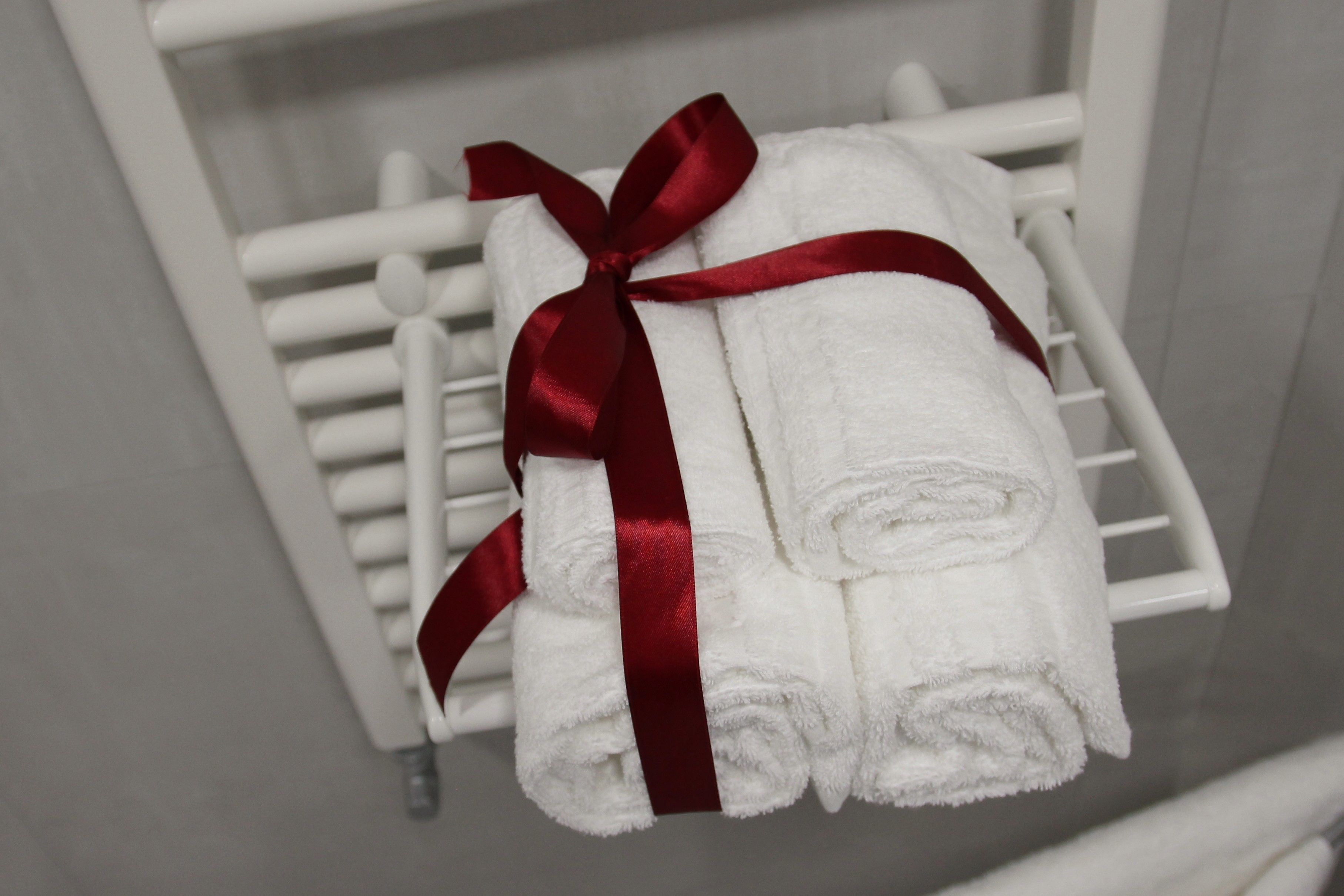 A white towel with a red ribbon on a white towel rack.