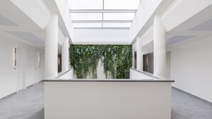 Un interior espacioso y moderno con una isla central, paredes blancas y un jardín vertical verde.