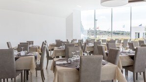 Un restaurante con mesas dispuestas para comer, amplias ventanas que ofrecen vistas del paisaje y una decoración interior moderna.