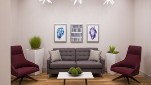 A modern living room with a grey sofa, two red armchairs, a white coffee table, and three framed artworks on the wall. - Fairfield by Marriott Inn & Suites Dayton Downtown (Dayton)