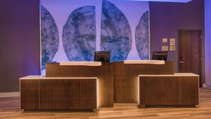 A reception desk with a modern design, featuring a large wall art piece and a wooden finish. - Fairfield by Marriott Inn & Suites Dayton Downtown (Dayton)