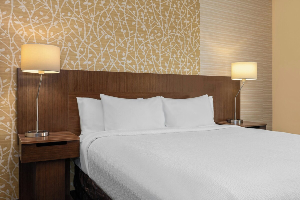Een hotelkamer met een groot bed, twee nachtkastjes en twee wandlampen.
