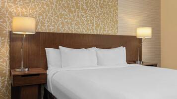 Une chambre d’hôtel avec un grand lit, deux tables de chevet et deux lampes fixées au mur.