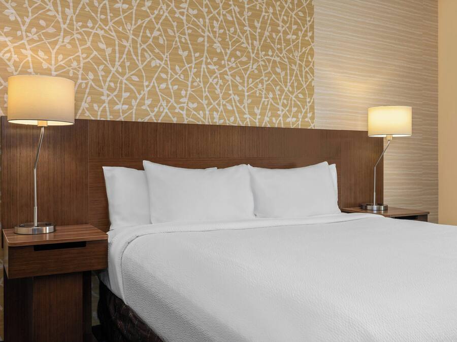 Une chambre d’hôtel avec un grand lit, deux tables de chevet et deux lampes fixées au mur.