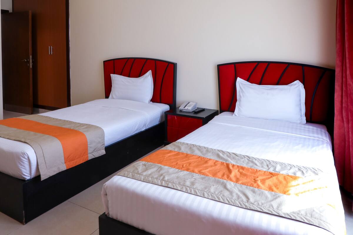 Two twin beds with red headboards, white bedding, and an orange accent on the bedspread.