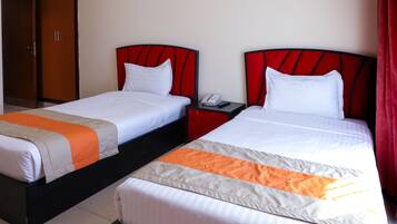 Two twin beds with red headboards, white bedding, and an orange accent on the bedspread.