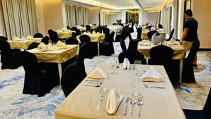 A banquet hall with multiple round tables, each set with white tablecloths and black chairs. - Wescott Plaza Hotel Apartment (Dubai)