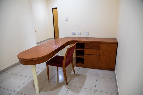 A corner room with a wooden desk, a red chair, and a wooden cabinet.