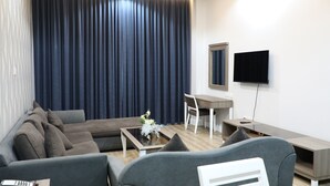 A modern living room with a sofa, coffee table, and a flat-screen TV mounted on the wall. - Wescott Plaza Hotel Apartment (Dubai)