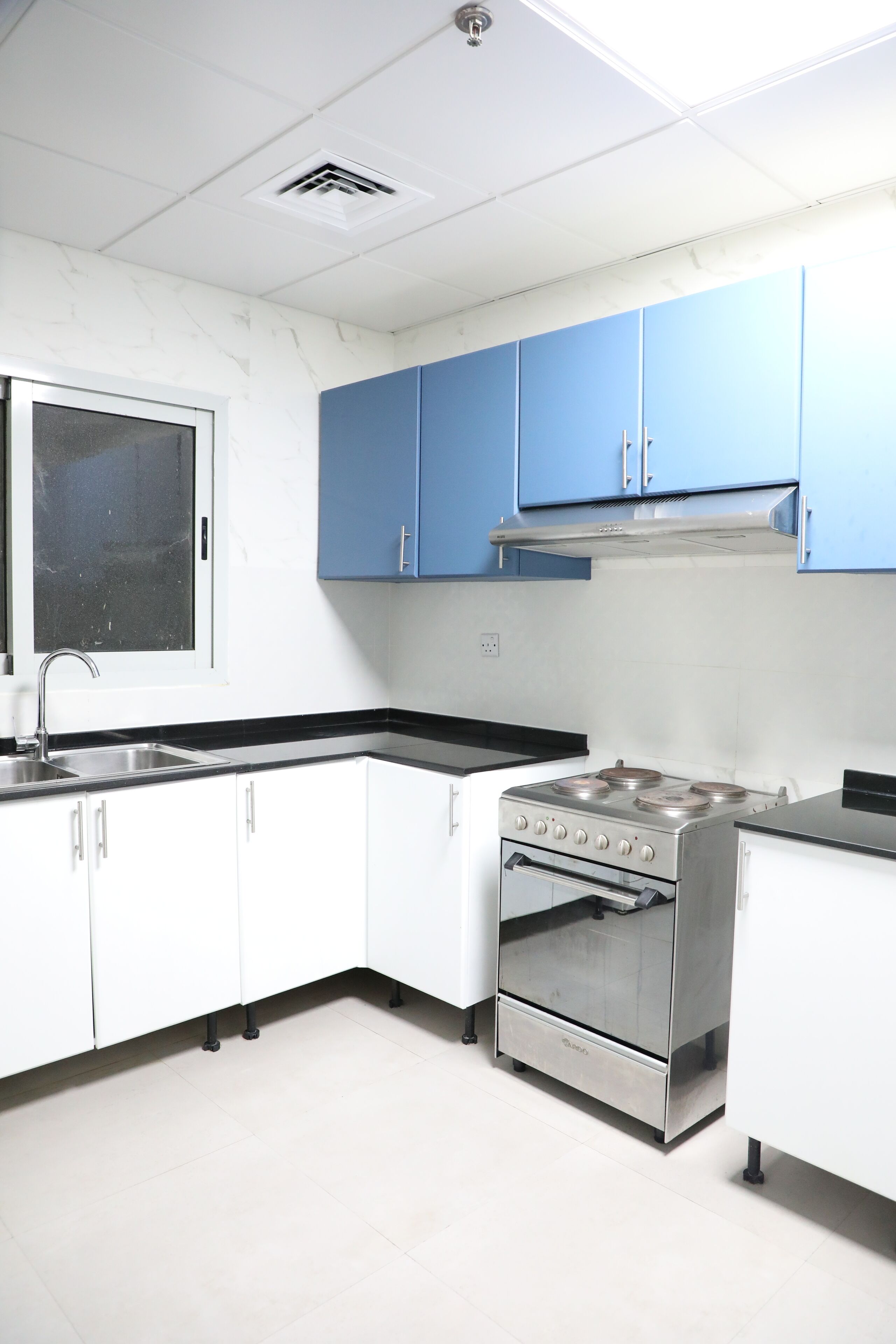 A kitchen with white cabinets, a stainless steel stove, and a window with a metal screen.