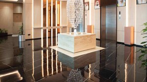 A modern lobby with a reflective floor, a central light fixture, and a reception desk. - Wescott Plaza Hotel Apartment (Dubai)