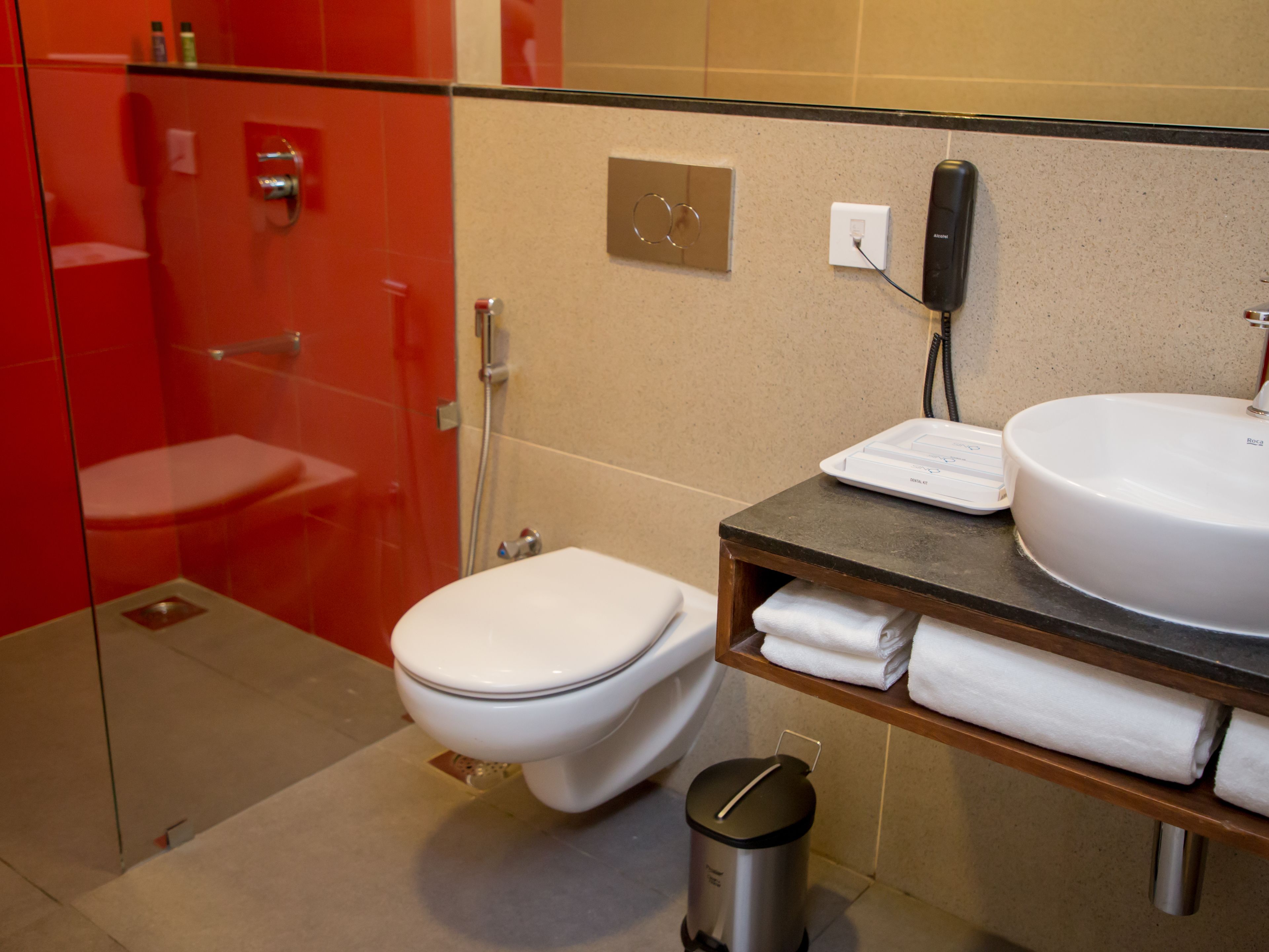 A modern bathroom with a glass-enclosed shower, a white toilet, a sink with a vanity, and a trash can.
