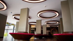 A modern lobby with circular ceiling lights, red cushioned seating, and a clean, minimalist design. - SinQ Prive (Candolim)