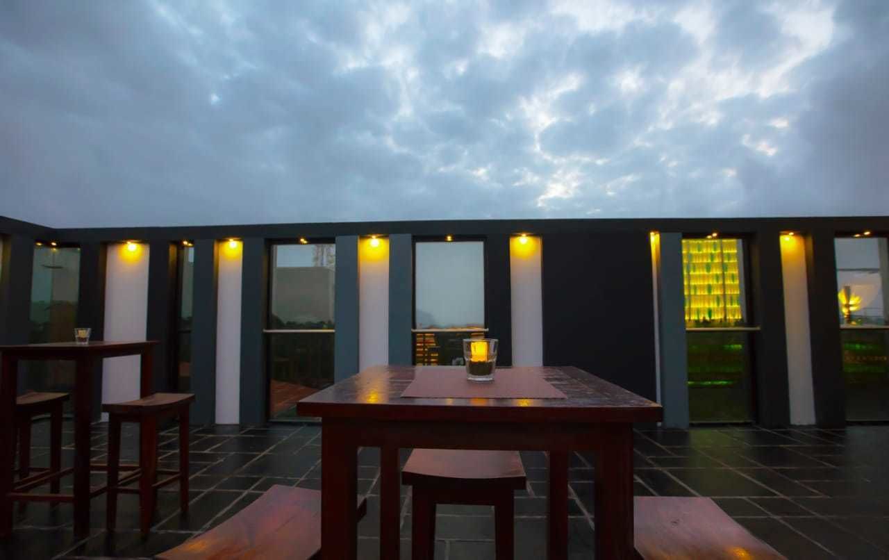 Uma área moderna para refeições ao ar livre, com mesa e cadeiras, janelas amplas e iluminação acolhedora.