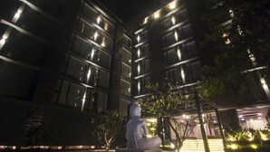 A modern building with multiple balconies and a statue in the foreground. - SinQ Prive (Candolim)