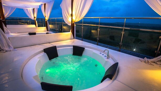 A hot tub with a view of the city at dusk. - SinQ Prive (Candolim)