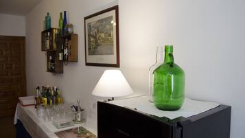 Una habitación con una mesa servida para una comida, una botella verde en la encimera y un cuadro en la pared.