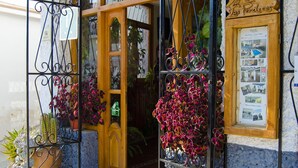 A hostel entrance with a wooden door, metal gate, and a signboard.