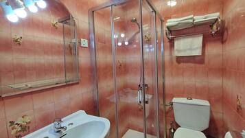 A bathroom with a glass-enclosed shower, a sink, and a toilet.