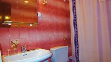 A bathroom with pink tiled walls, a white sink, a toilet, and a shower curtain.