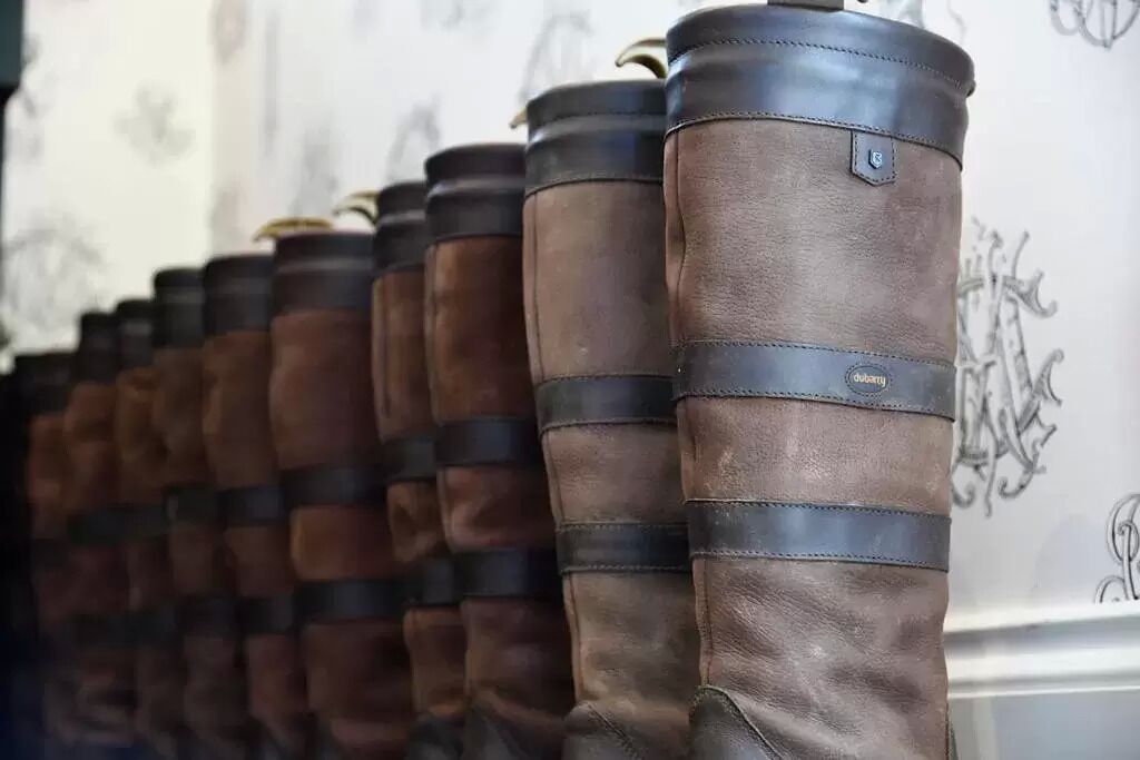 Een rij bruine leren laarzen met zwarte banden en een merklabel aan de zijkant.