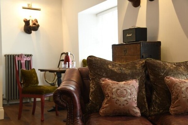 A cozy living room with a leather sofa, a vintage radio, and a bear head mounted on the wall. - Padstow Townhouse (Padstow)