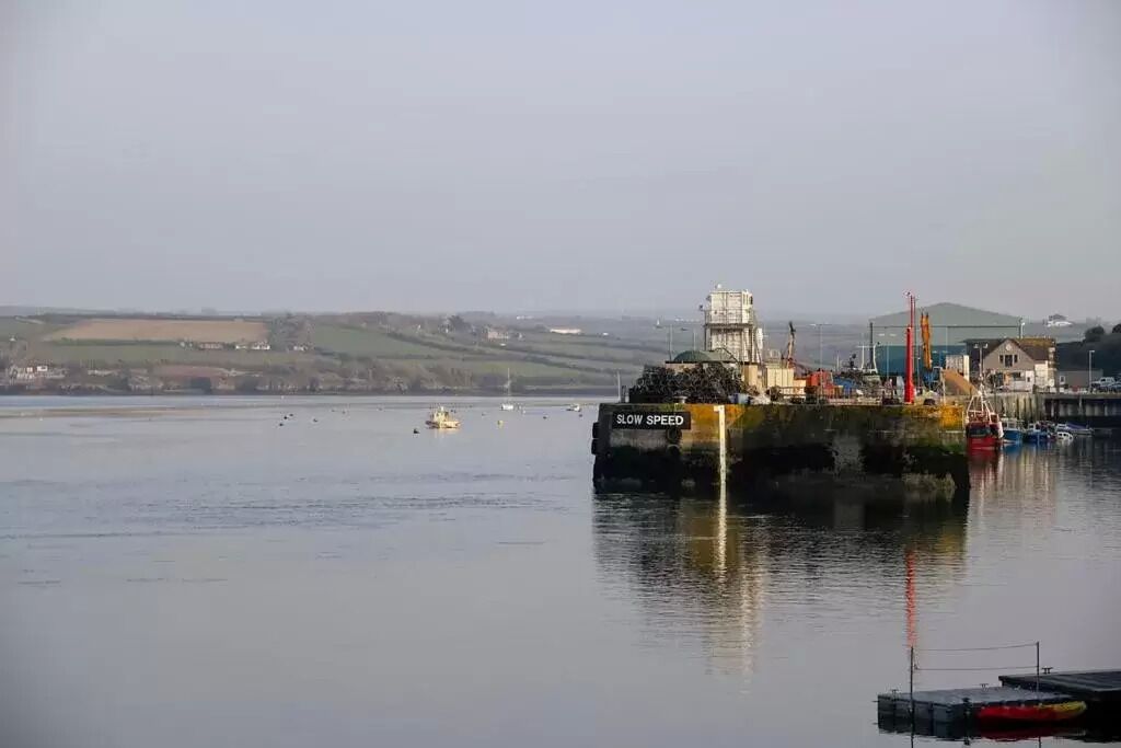 A harbor with a large ship docked, a pier, and calm water.