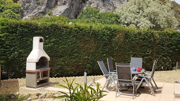 A patio with a stone barbecue grill, outdoor seating, and a view of a rocky hillside. - Air-conditioned 4-Room Villa with WIFI, Terrace, BBQ, and Parking - Sleeps 6 (Narbonne)