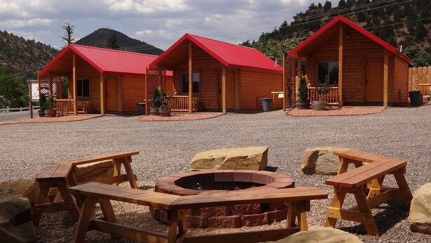 A row of wooden cabins with red roofs, each featuring a porch and a window.