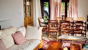 A living room with a sofa, wooden chairs, a coffee table, and a door leading outside. - Moaps Farm Bed and Breakfast (Haywards Heath)