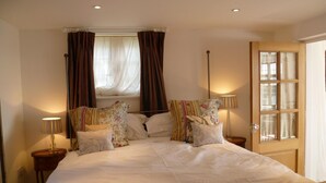 A neatly made bed with white linens, two bedside lamps, and a window with curtains. - Moaps Farm Bed and Breakfast (Haywards Heath)