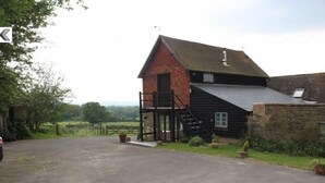 A red barn with a black extension, a staircase, and a gated driveway. - Moaps Farm Bed and Breakfast (Haywards Heath)