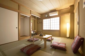 A traditional Japanese room with tatami flooring, a low wooden table, and cushions.