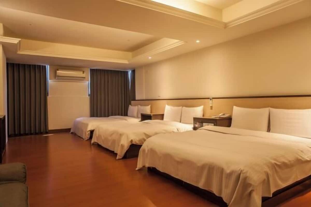 Habitación de hotel con dos camas, suelo de madera, techo con iluminación empotrada y equipo de aire acondicionado.