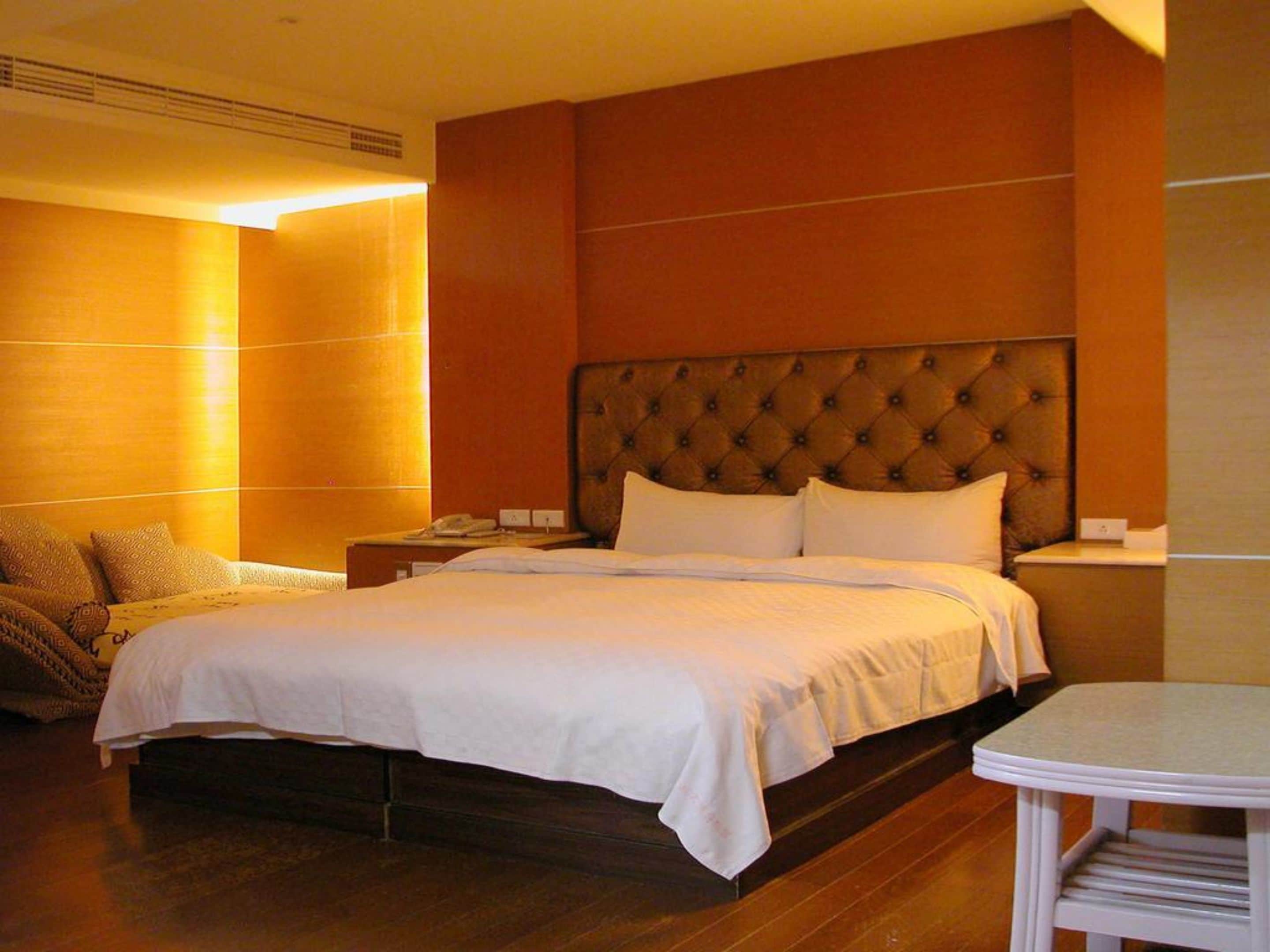 A hotel room with a large bed, a bedside table, and a small round table.