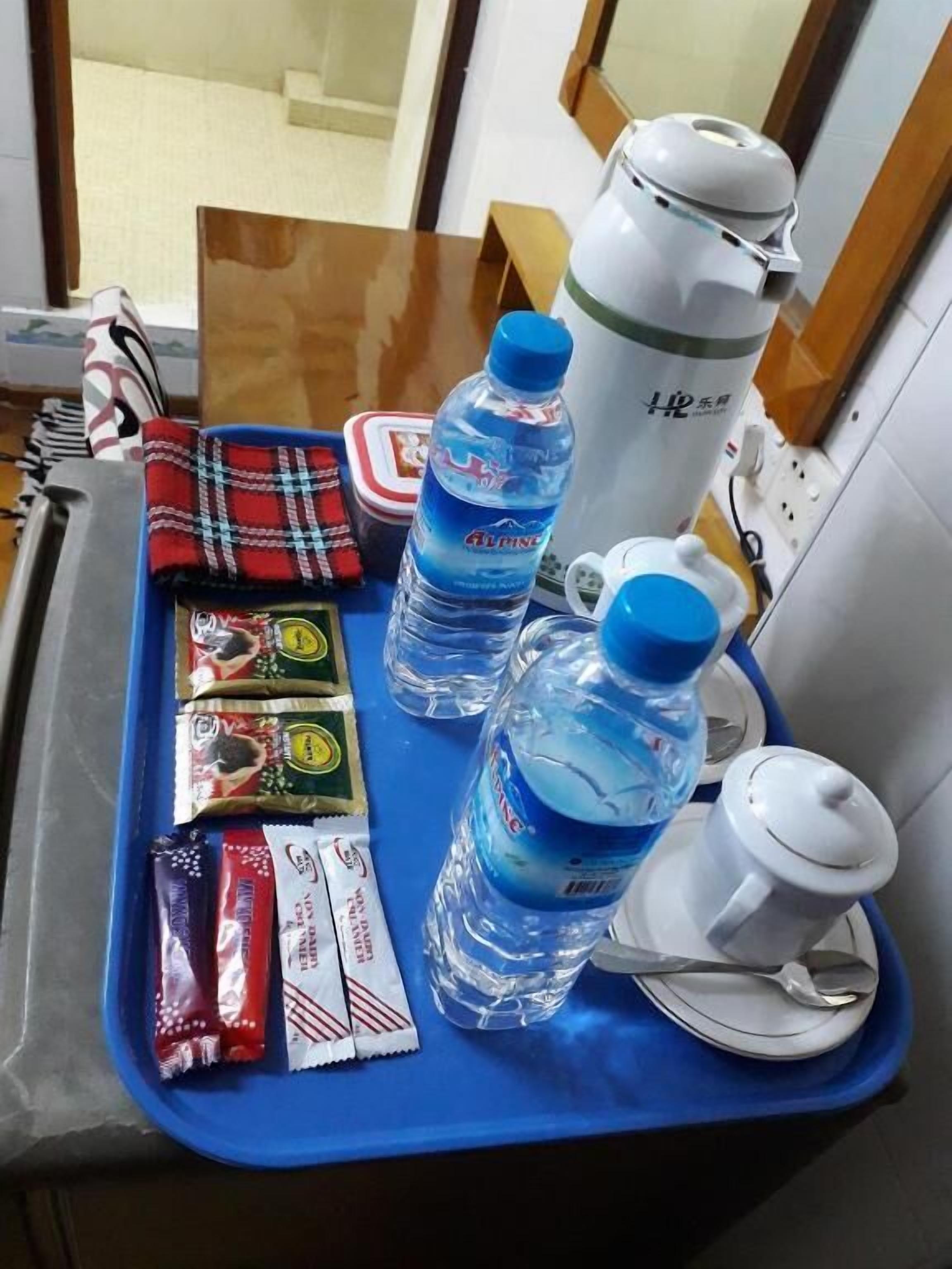 A tray with snacks, water bottles, a thermos, and a spoon on a table in a room.