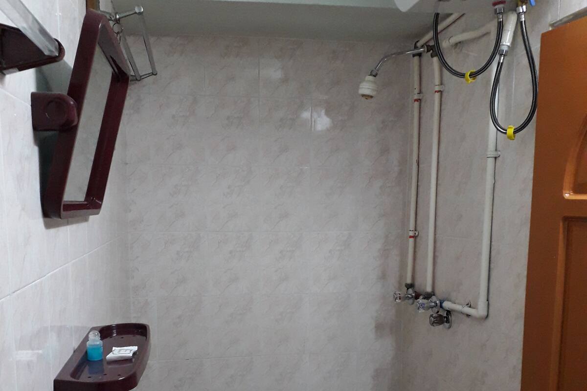 A small bathroom with a white sink, a mirror, and a shower area.