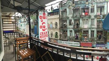 A balcony with wooden chairs and a view of old buildings.